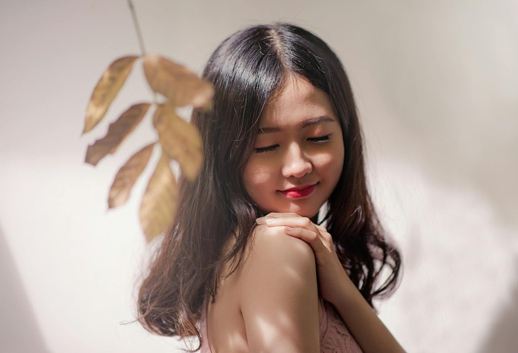 Peaceful young woman with eyes closed, embracing serenity with a gentle smile.